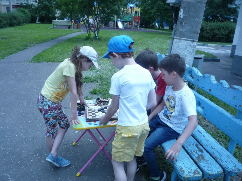 Дети играют в шашки на свежем воздухе